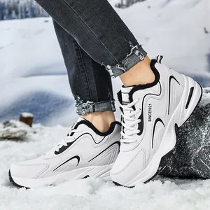 Gros plan de baskets en cuir blanc avec doublure en fourrure noire sur sol enneigé
