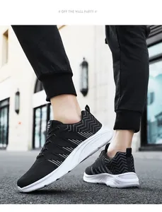 Side view of black breathable knit sneakers with white wave embroidery on street background