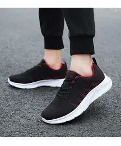 Close-up of black breathable mesh sneakers with red stripes on a street surface