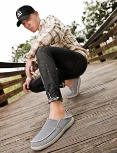 Detailed close-up of grey canvas loafers featuring raw edge stitching and textured fabric