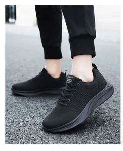 Close-up of black breathable fly-knit men's sneakers on a road surface in outdoor light