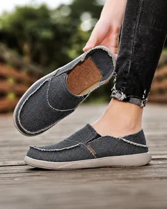 Detail of dark grey canvas loafers with frayed edges and cork texture insole on feet