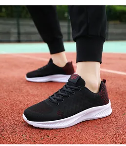 Dettaglio di sneaker in mesh nero con inserti rossi sul tallone su una pista da atletica
