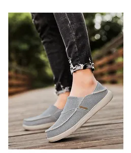 Close-up of gray canvas loafers on a wooden walkway showing stitching and elastic bands