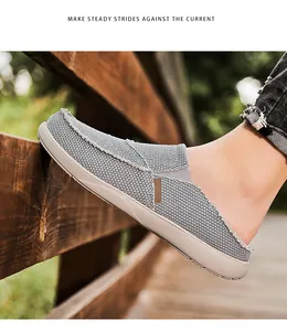 Detail of grey canvas mule loafers with frayed edges and stitched toe on wood fence