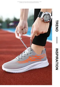 Detailed shot of grey mesh sneakers featuring vibrant orange flame patterns on a red track