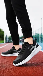 Gedetailleerd zijaanzicht van zwart-witte hardloopschoenen op een rode atletiekbaan