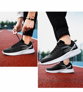 Zwarte leren heren sneakers met dikke witte antislipzool op een outdoor atletiekbaan