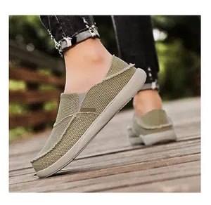 Army green canvas loafers on feet walking on a wooden path with frayed edge detail