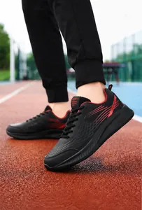 Dynamisch zijaanzicht van zwarte herensneakers met rode accenten op een atletiekbaan