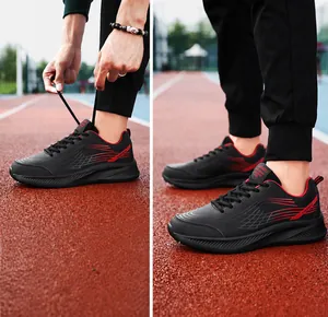 Detailweergave van zwarte herensneakers met rode kleurverloopstrepen op een atletiekbaan