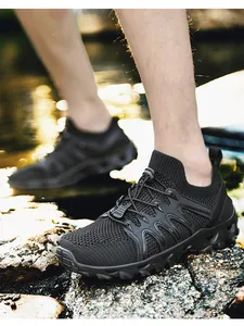 Close-up of black breathable mesh outdoor hiking shoes on rocky stream terrain
