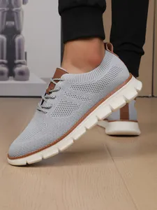 Detail of grey breathable knit mesh men's shoes with brown leather accents and thick white sole