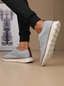 Detail of grey knitted sneakers showing brown leather accents and thick white anti-slip sole
