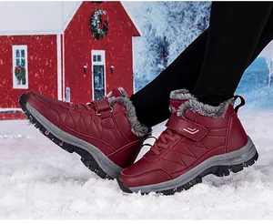 Details von burgunderroten Winterstiefeln mit Fellfutter und Klettverschluss im Schnee