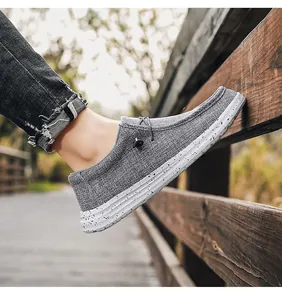 Men's grey canvas loafers with elastic laces and splatter-textured sole in a park