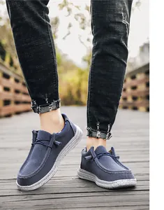 Detail of dark blue canvas loafers with speckled white rubber soles on a wooden bridge