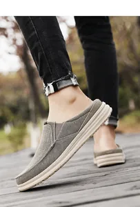 Outdoor close-up of grey canvas backless loafers featuring thick white rubber soles
