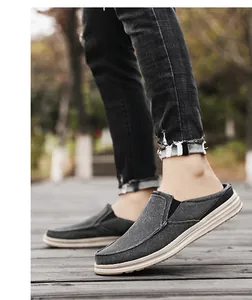 Detail view of grey canvas mule sneakers with thick rubber soles on a wooden path