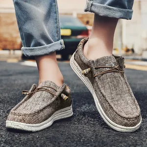Detalle de mocasines de lona en asfalto, mostrando suelas de goma moteadas y tela de lino