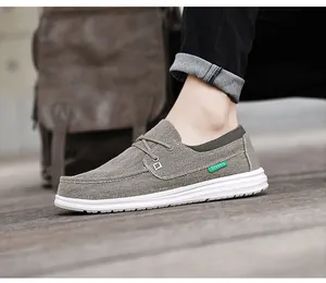 Zijaanzicht van grijze canvas herenloafers met groen label op houten vloerbedekking