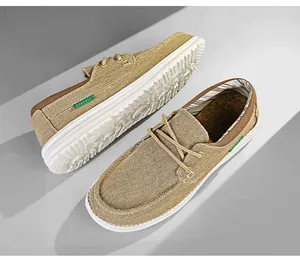 Detail van kaki canvas loafers voor heren met witte zolen en veters.
