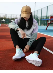 Dettaglio scarpe da corsa in mesh bianco con strisce verde menta su pista atletica