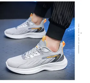 Detail van grijze mesh hardloopschoenen met dikke witte zolen en oranje treklipjes