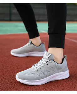 Dettaglio scarpe da corsa grigie traspiranti con suole bianche sulla pista