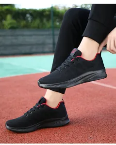 Dettaglio scarpa da corsa nera in mesh traspirante con accenti rossi su pista atletica