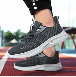Dettaglio scarpe da corsa grigie da uomo con tomaia in rete su pista di atletica rossa