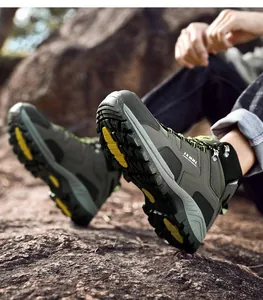Detail of gray hiking boot with rugged rubber outsole and yellow accents on rocks