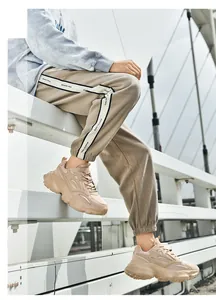 Detalle de zapatillas retro gruesas con pantalones joggers caqui en un entorno urbano