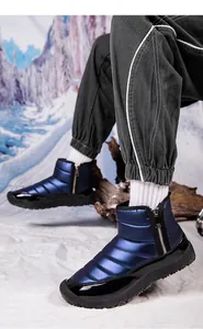 Close-up of waterproof navy quilted snow boots with side zipper on winter snow background