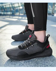 Dettaglio del tessuto a maglia traspirante e logo KENTI rosso su scarpe sportive grigie