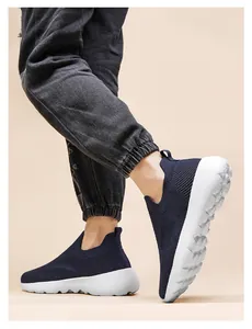 Detail of dark blue 3D knit slip-on sneakers with thick white cushioned soles on foot