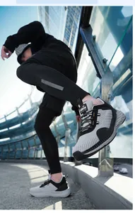 Scatto dinamico di sneakers da uomo in maglia con rete grigia e dettagli in pelle nera