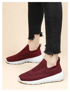 Detail of burgundy 3D knit breathable slip-on walking shoes on model with frayed black jeans