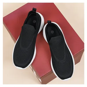 Detail view of black 3D knit slip-on sneaker with thick white sole on shoe box