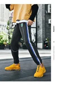 Détail du jogging noir avec rayures latérales dégradées bleues et logo sportif
