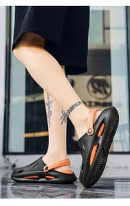 Close-up of men's black and orange platform clogs worn by a model on an urban street