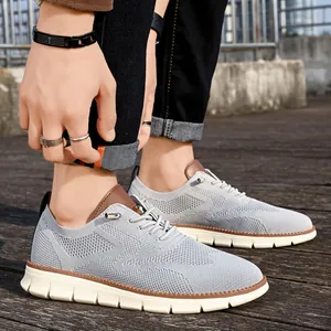 On-foot view of grey breathable mesh sneakers with brown trim on a wooden deck