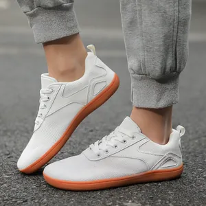White breathable knit wide toe barefoot sneakers with gum rubber soles on asphalt background