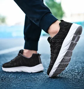 Dynamic street view of men's black knit running shoes with thick cushioned white soles