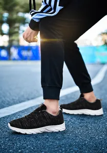 Detail view of breathable black fly-woven fabric and anti-slip white rubber sole on sneakers