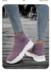 Detail view of purple knit sock sneakers with thick white anti-slip soles on a wooden path