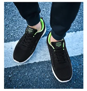 Top view of black mesh running shoes with neon green lining on urban asphalt road