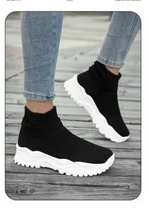 Close-up of black breathable knit sneakers with thick white rubber soles on a model