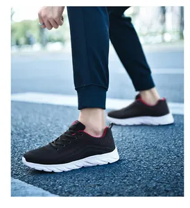 Close-up of lightweight black knit running shoe with red lining on asphalt road