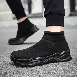 Men's black knitted sock sneakers with wavy thick soles on an asphalt outdoor background